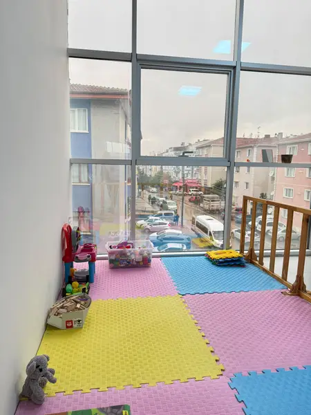 Renkli yumuşak zeminli, ahşap çitle ayrılmış oyun alanı