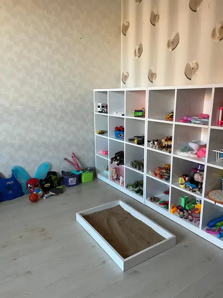 Oyuncak rafları ve kum havuzu bulunan oyun terapisi odası